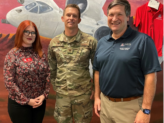 Bruce Grissom, Director of the Veterans Education and Transitions Services program and Jaye Ferrone, our Online Veteran Support Specialist pose for a photo with Colonel Mills in front of an A-10 mural painted by UA vets.