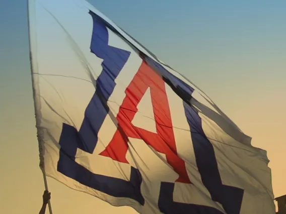 A University of Arizona flag is seen waving as dusk falls over Tucson