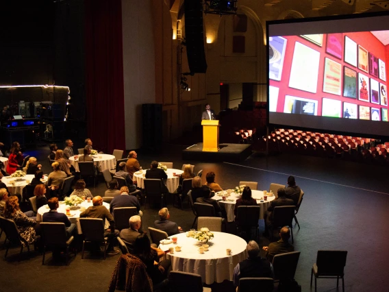 An audience listens to a speaker at a podium present on Arizona Arts in Centennial Hall