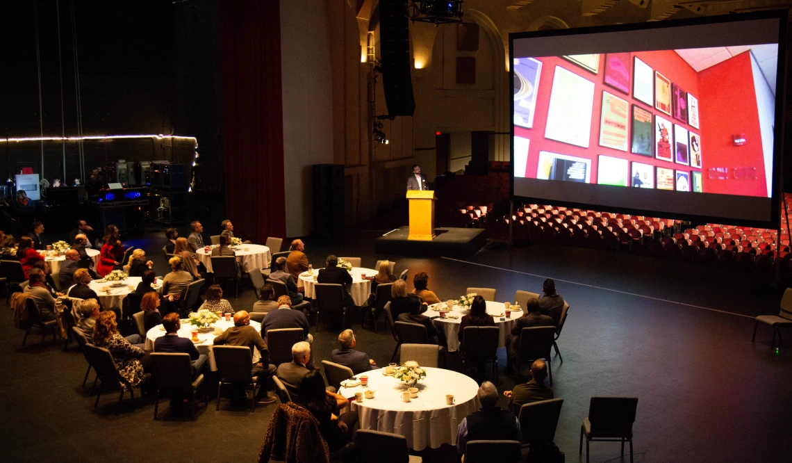 An audience listens to a speaker at a podium present on Arizona Arts in Centennial Hall