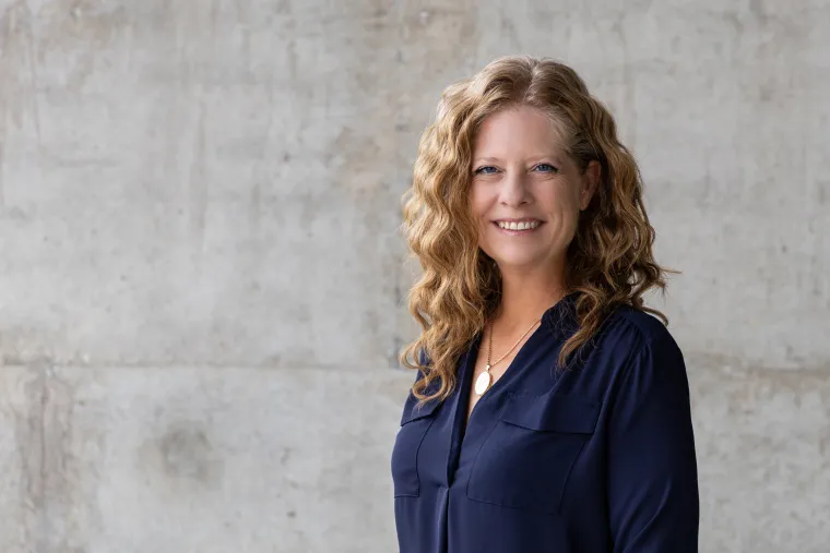 A photo of a woman with curly long red hair in a blue blouse