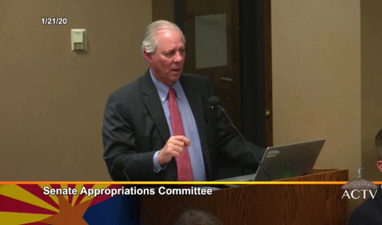 President Robbins is seen standing at a podium as makes remarks to the Senate Appropriations Committee at the State Legislature