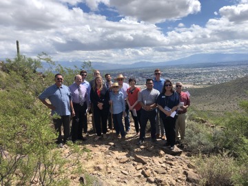 Photo of a group of community leaders and university staff pose for a photo atop the University of Arizona's Tumamoc Hill