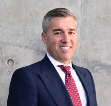 Portrait of Vice President for Government and Community Relations Steve Voeller, he is wearing a red tie, white dress shirt and navy blue suit