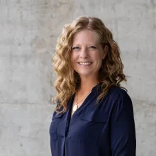 A photo of a woman with curly long red hair in a blue blouse