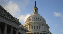 A photo fo the U.S. capitol dome with a blue sky seen behind it